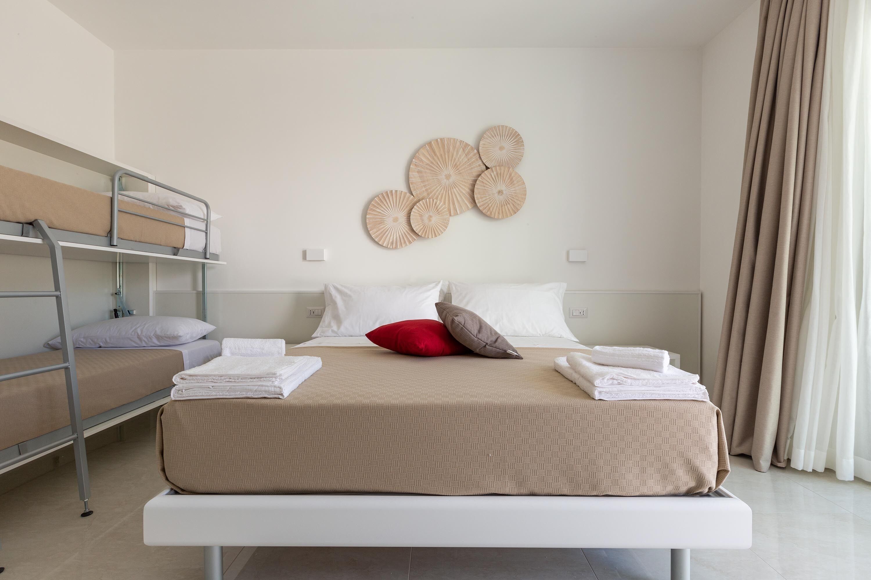 Une chambre d’hôtel équipée d’un lit superposé, d’un lit simple et d’un panneau décoratif fixé au mur.