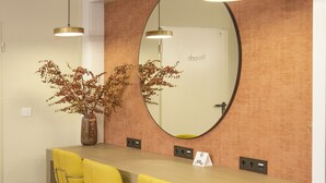 A reception area with a long counter, three yellow chairs, a large mirror, and a sign reading "Business Center".