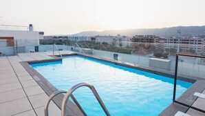A rooftop swimming pool with a clear view of the cityscape in the background.