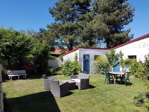 A patio area with outdoor furniture, a white building with a blue door, and surrounding greenery. - Bed and Breakfast in an Estaminet (DRINCHAM)