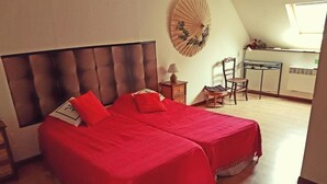 A bedroom with two beds, a desk, and a chair.