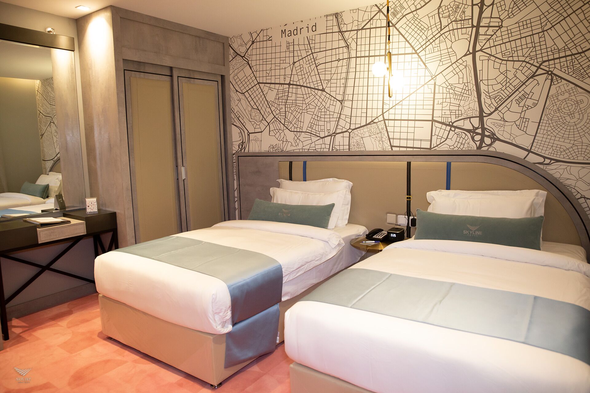 Hotellihuone, jossa on kaksi sänkyä, työpöytä ja seinällä Madridin kartta.