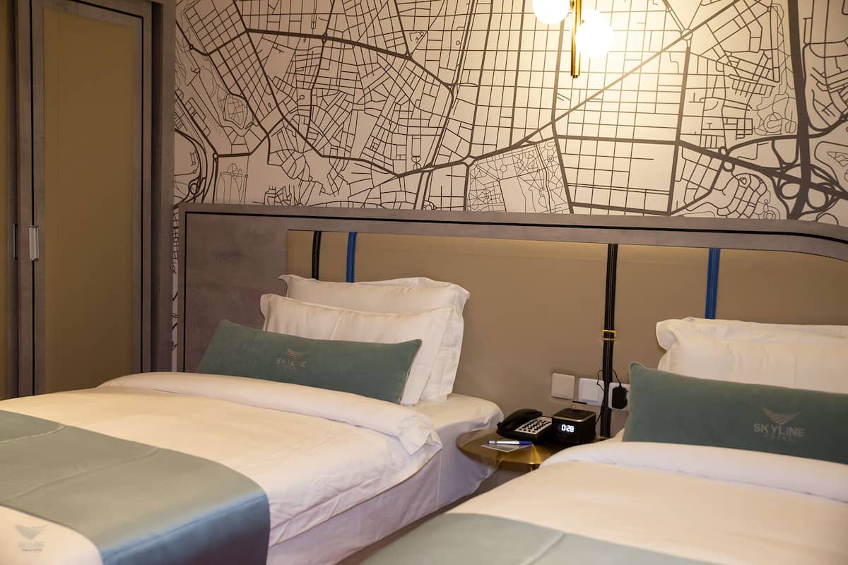 A hotel room with two beds, a map on the wall, and a phone on the nightstand.