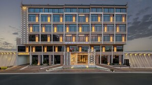Un hotel moderno con una fachada simétrica, varios pisos y una entrada destacada.