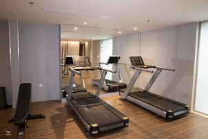 A fitness room with treadmills, a bench, and a mirror.