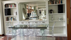 A modern kitchen with a glass dining table, clear chairs, and white cabinetry. - Chalet DE Lujo (Somo)