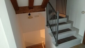 Una escala amb bigues de fusta, barana metàl·lica i un lluminari.