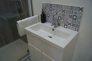 A bathroom with a white sink, a glass bottle, and a patterned tile backsplash. - Vale View - Sleeps 6 - Pets Ok - Garden - Parking (Melton Mowbray)