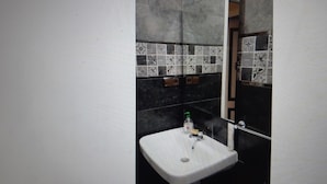Une salle de bain avec un lavabo blanc, des carreaux à motifs noirs et blancs et un miroir.