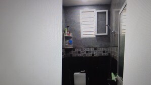 Une salle de bain comprenant des toilettes, un lavabo et un espace douche.
