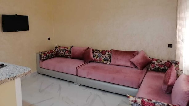 Un salon comprenant un canapé, un téléviseur à écran plat fixé au mur et un comptoir en marbre.