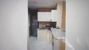 Une cuisine avec des meubles blancs, un réfrigérateur noir, un évier et une cuisinière.