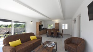 En moderne stue med en brun sofa, et sofabord og et spiseområde med stole og et bord.