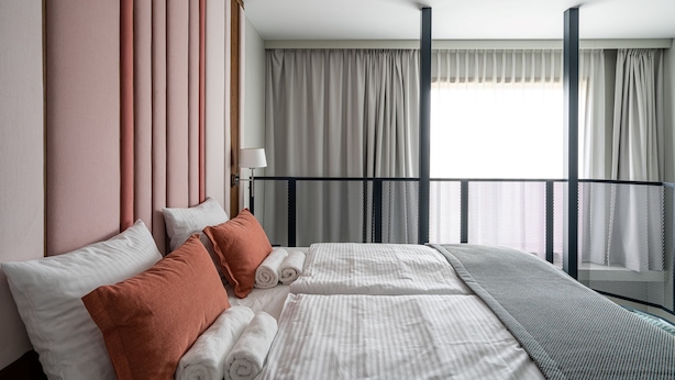 A modern hotel room with a large bed, a balcony with a railing, and a view of the city. - RentPlanet - Apartamenty Gwarna (Wroclaw)