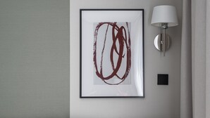 A modern living room with a grey sofa, a framed abstract painting, a wall-mounted lamp, and a wooden coffee table with two white cups. - RentPlanet - Apartamenty Gwarna (Wroclaw)