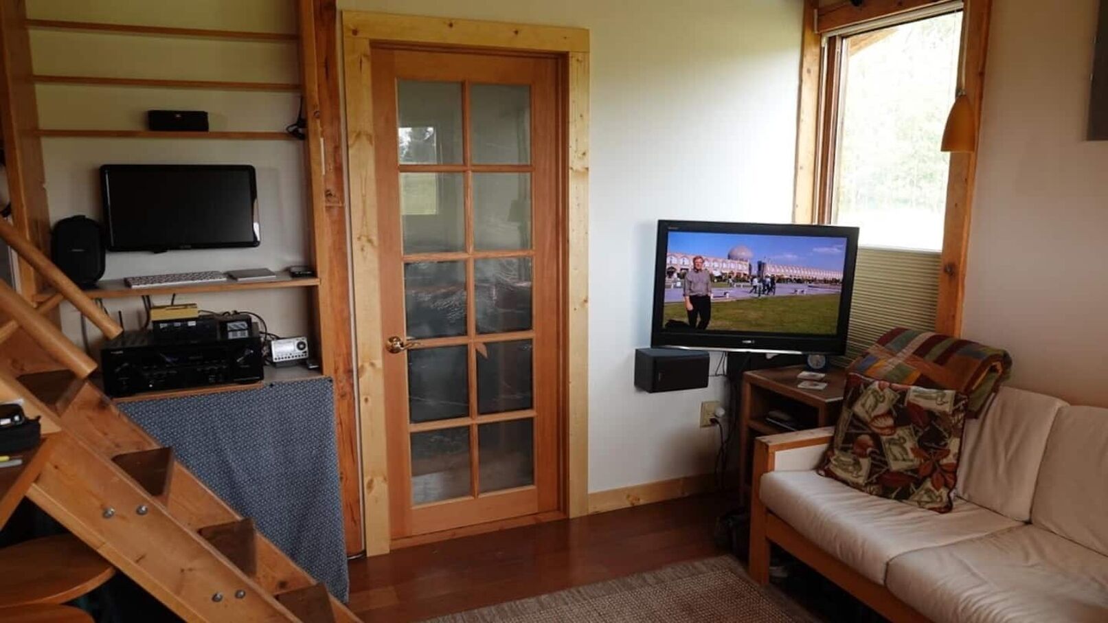 Un salon chaleureux avec un escalier en bois, une télévision et un canapé.