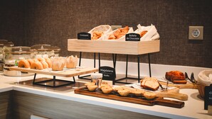 A bakery display with labeled sections for croissants, chocolate rolls, muffins, and other baked goods.