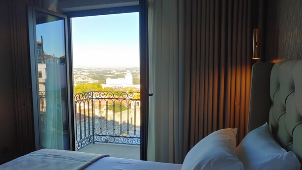 A hotel room with a bed, a view through a glass door, and a curtain.