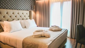 A neatly made bed with white linens, a headboard with a geometric pattern, and a pair of towels on the bed.