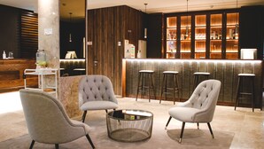 A modern bar area with a marble reception desk, two bar stools, and a round coffee table.