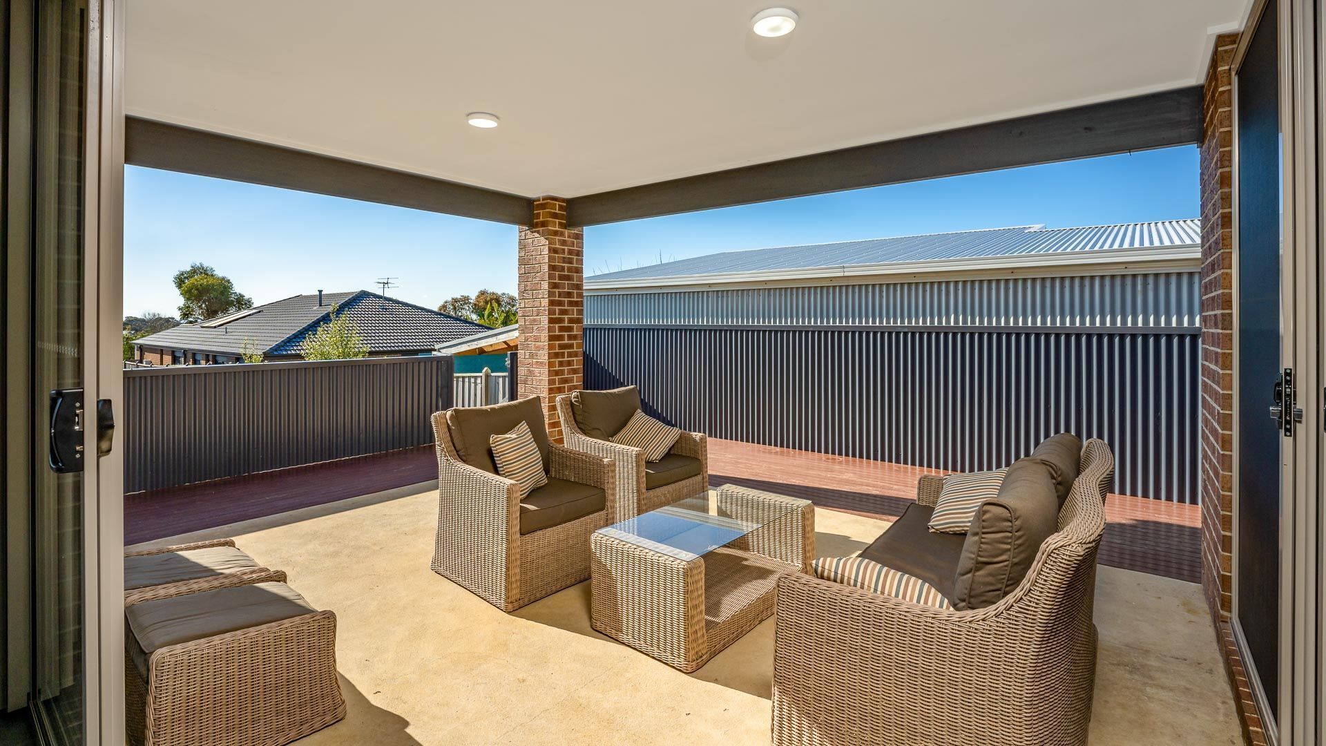 Un patio techado con mobiliario de mimbre y vistas a casas vecinas.