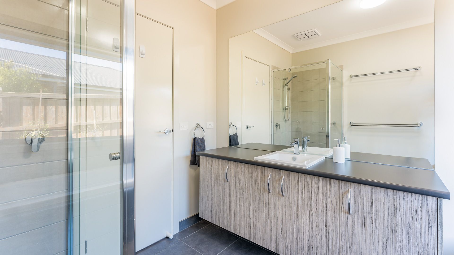 A modern bathroom with a glass shower enclosure, a vanity with a mirror, and a towel rack.