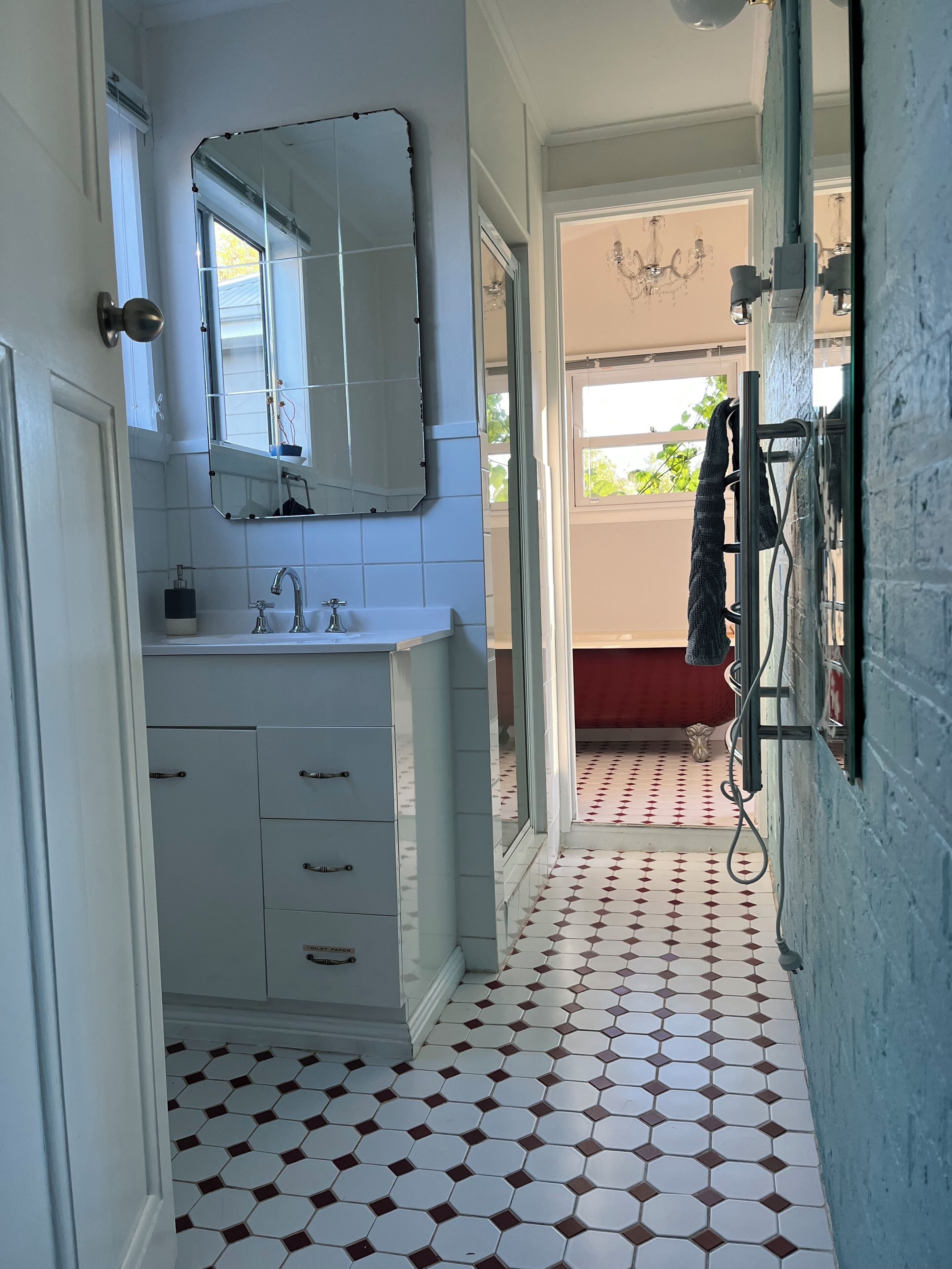 A bathroom with a white sink, mirror, and tiled floor.