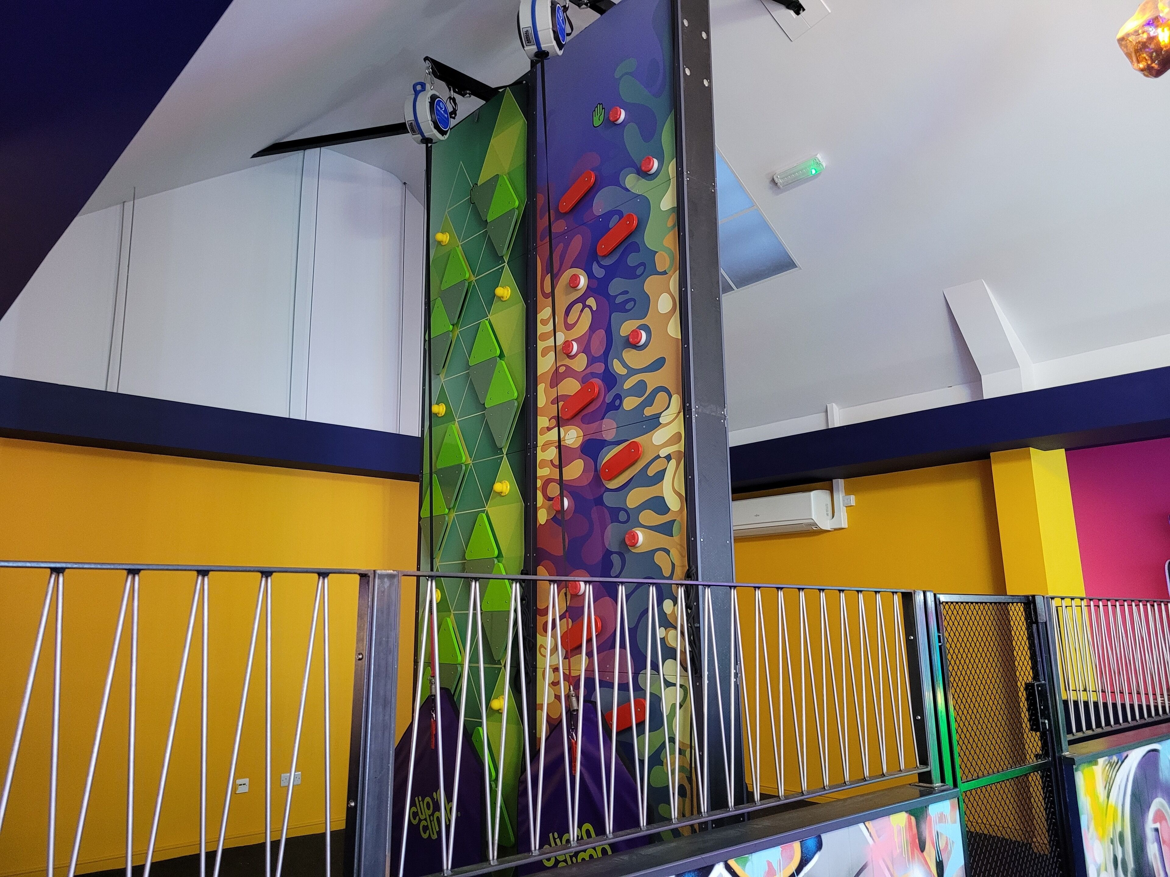 A colorful climbing wall with geometric patterns and safety railings.