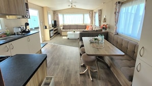 A well-lit RV interior with a kitchenette, dining area, and seating space. - St Osyth- Sleeps8-freeparking-wifi-holidaypark (Clacton-on-Sea)