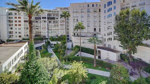 A residential building with multiple balconies, a central courtyard with palm trees, and a clear blue sky.