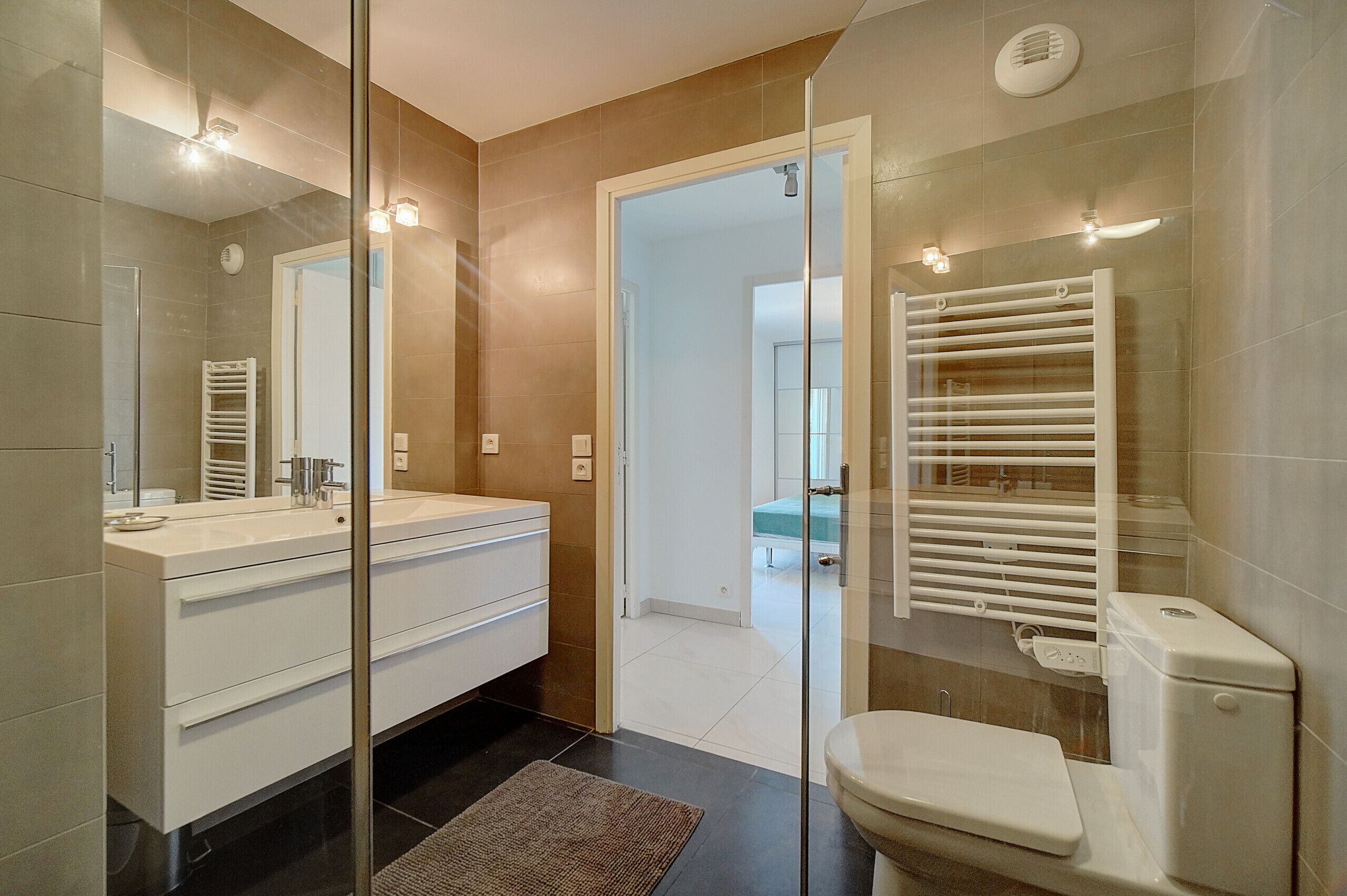 A modern bathroom with a glass shower enclosure, a white sink, and a toilet.