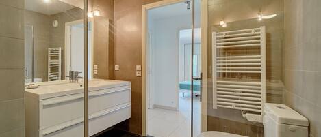 A modern bathroom with a glass shower enclosure, a white sink, and a toilet.