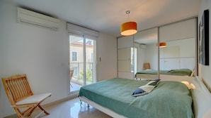 Une chambre à coucher avec un lit, une chaise, une grande fenêtre et un miroir.