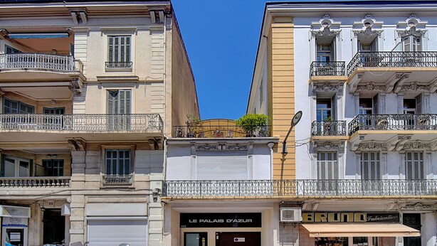 Un immeuble dont les devantures de magasin portent les noms « Le Palais d’Azur » et « Bruno ».