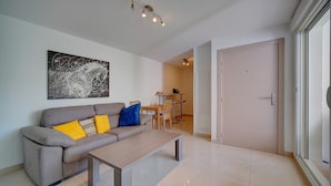 Un salon moderne avec un canapé gris, une table basse en bois et un coin repas à l’arrière-plan.