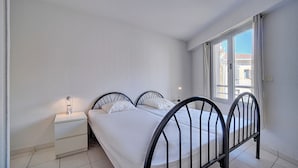 A bedroom with a bed, a nightstand, a lamp, and a window. - 3 PIECES SPACIEUX CANNES CENTRE A2B067 (Cannes)