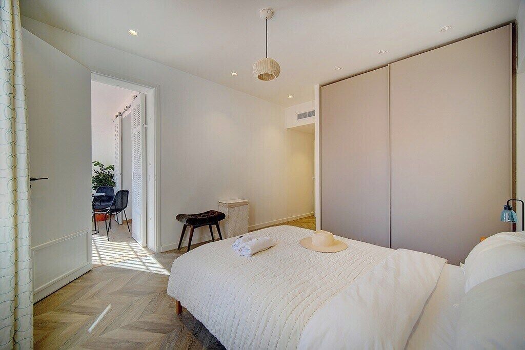 Een slaapkamer met een groot bed, een kledingkast en een zithoekje met een stoel en een tafeltje.