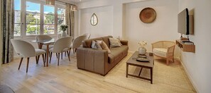 Uma sala de estar moderna com sofá, mesa de jantar, cadeiras e uma TV.