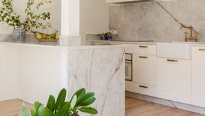 A modern kitchen with white cabinetry, a marble countertop, and a central island. - Gran Hotel Brillante (Muros de Nalon)