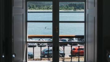 A view through a bay window with a lake and parked cars visible.