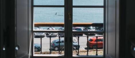 Vista a través de un ventanal con un lago y coches aparcados.