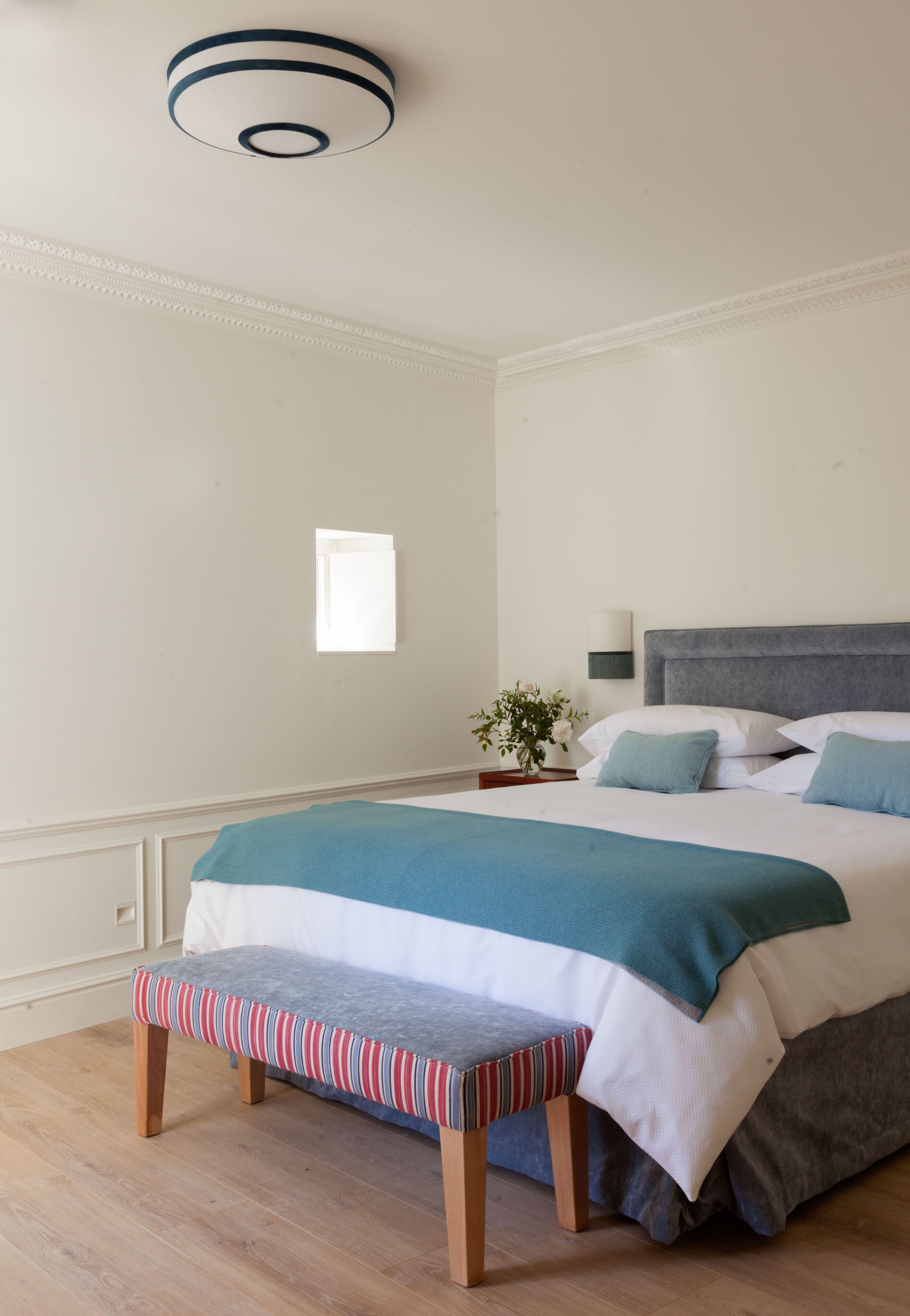 A neatly arranged bedroom with a bed, bedside table, and bench.