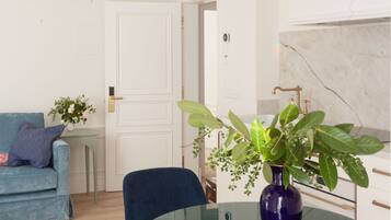 Una sala moderna con una mesa de vidrio, sillas azules, un sofá y una planta en maceta.