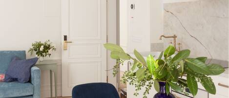 Una sala moderna con una mesa de vidrio, sillas azules, un sofá y una planta en maceta.