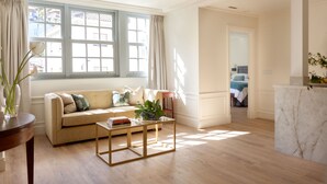 A living room with a beige sofa, a coffee table, and a window with curtains. - Gran Hotel Brillante (Muros de Nalon)