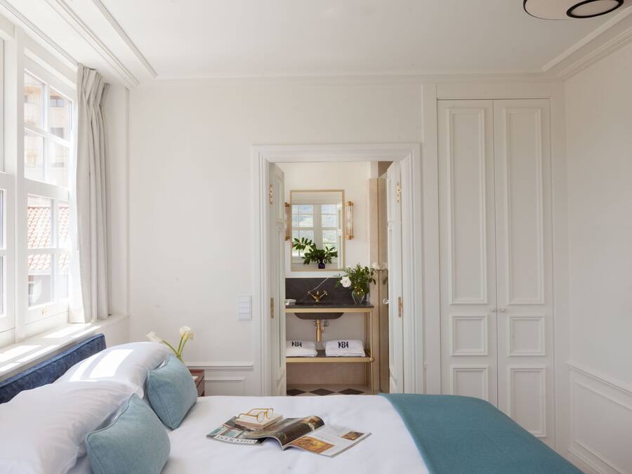Ein Hotelzimmer mit Bett, Schminktisch mit Spiegel und Blick ins Freie durch ein Fenster.