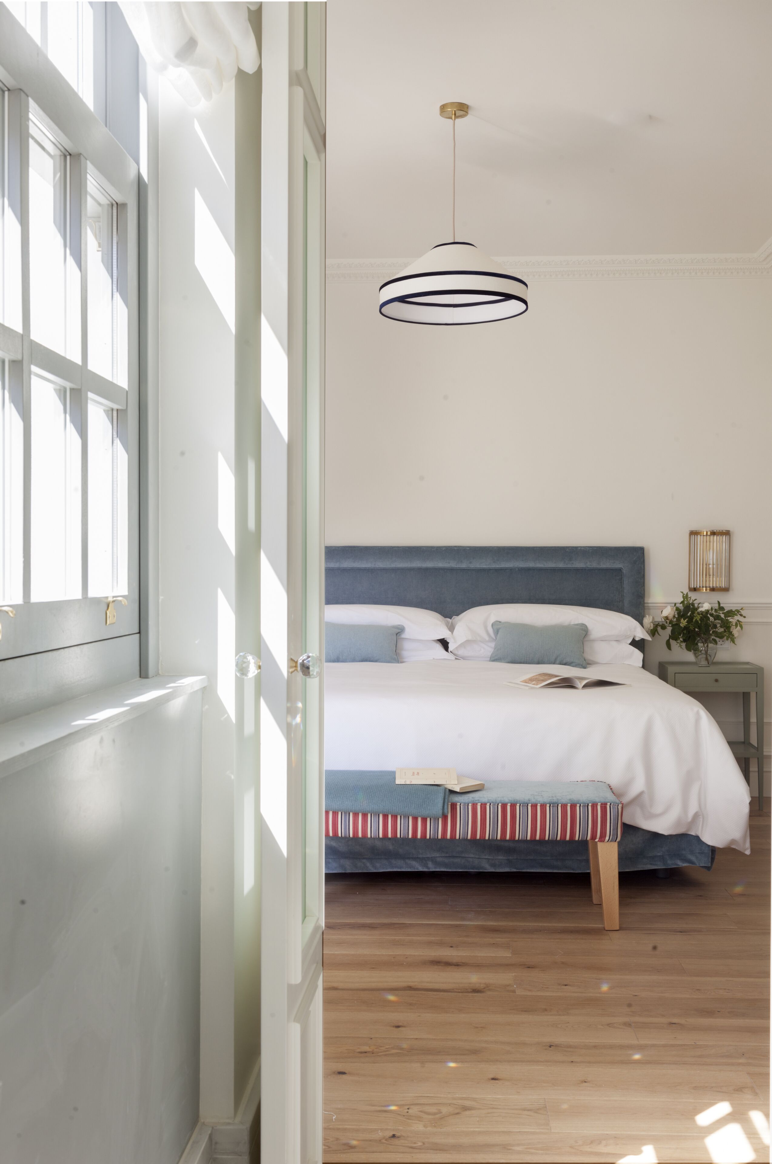 A bedroom with a bed, bedside table, and a hanging light fixture.