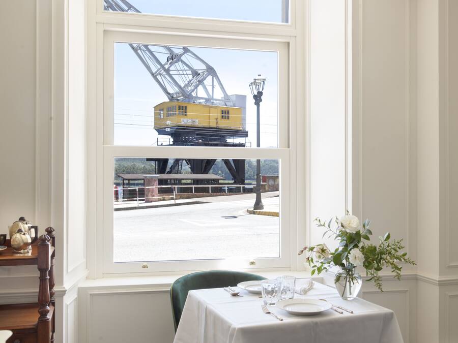 Un comedor con una mesa lista para dos, vista a través de una ventana de una obra en construcción, y un candelabro.