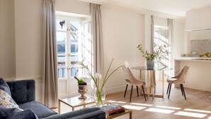 A modern living room with a sofa, a glass coffee table, and a dining area with chairs. - Gran Hotel Brillante (Muros de Nalon)