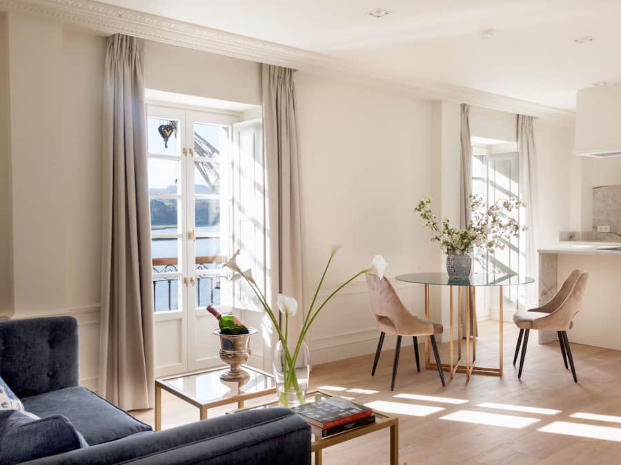 Una sala de estar moderna con un sofá, una mesa de centro de vidrio y una zona de comedor con sillas.